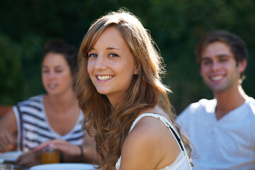 Happy, woman and portrait in backyard with friends at a table with young people and smile. Lunch, home garden and group ready for eating on a summer break together and relax outdoor of a house