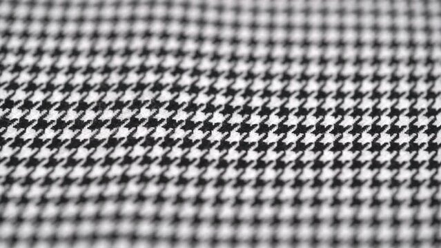 closeup of texture of tweed fabric houndstooth, classic woolen pattern, rotating. black and white houndstooth pattern. woven textile background.