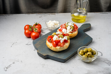 Board with Cretan appetizer Dakos, with ripe tomatoes and feta cheese. A classic snack.