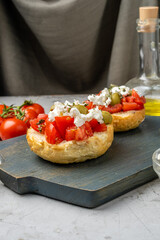 Toasted bun with ripe tomatoes, feta cheese and olive oil, Dacos. Vertical photo. Greek dish.
