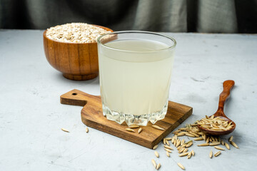 Glass glass with fermented oat drink, light table. - obrazy, fototapety, plakaty