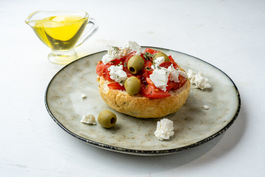 Dakos or ntakos, Greek appetizer of bread, tomatoes and olive oil with raw feta, light table.