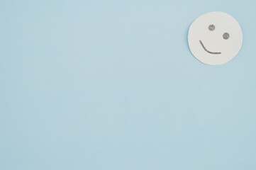 Smiley from white paper on blue background. World Day of Peace. Day Against Humiliation. International Day Of Human Fraternity. International Day of Living Together in Peace
