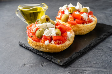 Appetizing appetizer dakos-Greek cuisine, bread with ripe tomatoes and feta cheese, dark background. Close-up.
