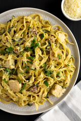 Homemade Creamy Chicken Bacon Pesto Pasta on a Plate on a black background, top view. Flat lay, overhead, from above.