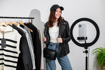 Fashion blogger recording vlog about clothes. Female blogger or stylist standing in front of camera showing clothes, filming vlog episode for her channel. Content creator concept.