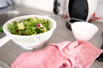 Close-up of fresh organic healthy herbs and greens in the vegetable dryer on the kitchen table