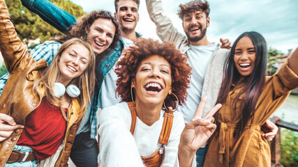 Fototapeta premium Big group of friends taking selfie picture smiling at camera - Laughing young people celebrating standing outside and having fun - Portrait photography of teens guys and girls enjoying vacation