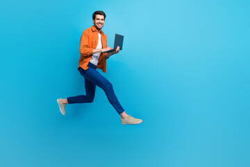 Fototapeta na wymiar Full body profile portrait of active excited person jumping rush use netbook empty space ad isolated on blue color background