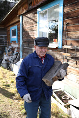 An elderly man collects firewood in a Russian village in winter