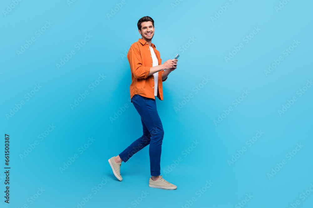 Aufkleber Full body profile portrait of attractive cheerful person use smart phone walking empty space isolated on blue color background