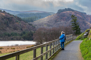 Fototapeta na wymiar Blond mature women in casual clothing walking on a path by Lower Lake in the Wicklow Mountains