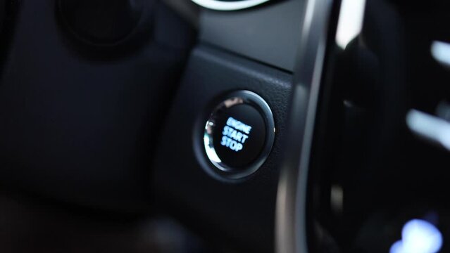 Close up of finger pushing orange start engine button in a car