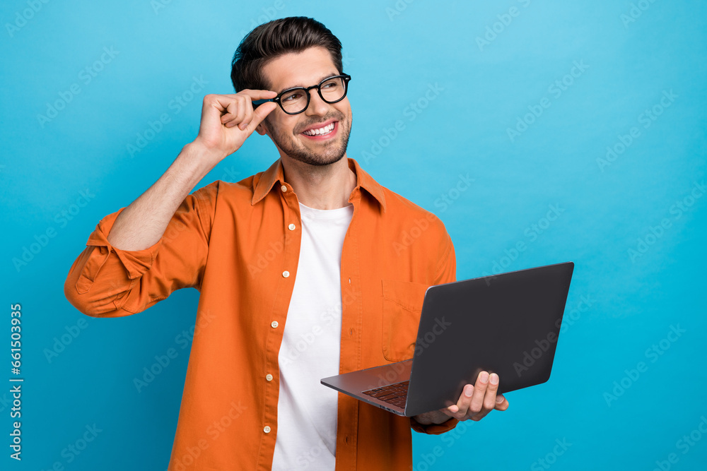 Poster portrait of cheerful minded person arm touch eyewear hold netbook look empty space isolated on blue 