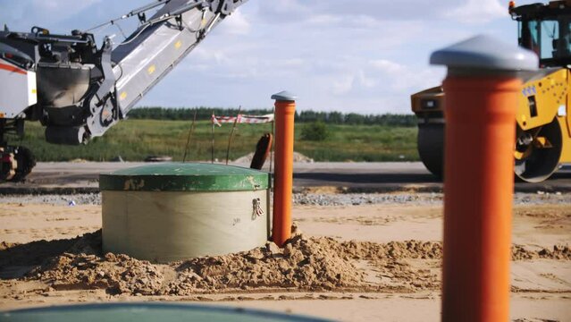 Containers with pipes dug in ground at new highway construction site. Underground materials storage with large tanks at countryside
