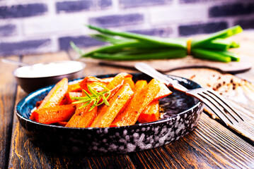 Fried carrots with green herbs in baking tray, close up - 661506361
