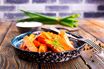 Fried carrots with green herbs in baking tray, close up - 661506369