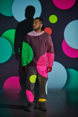 handsome man in pink hoodie standing and looking away in digital projector lights, fashion concept