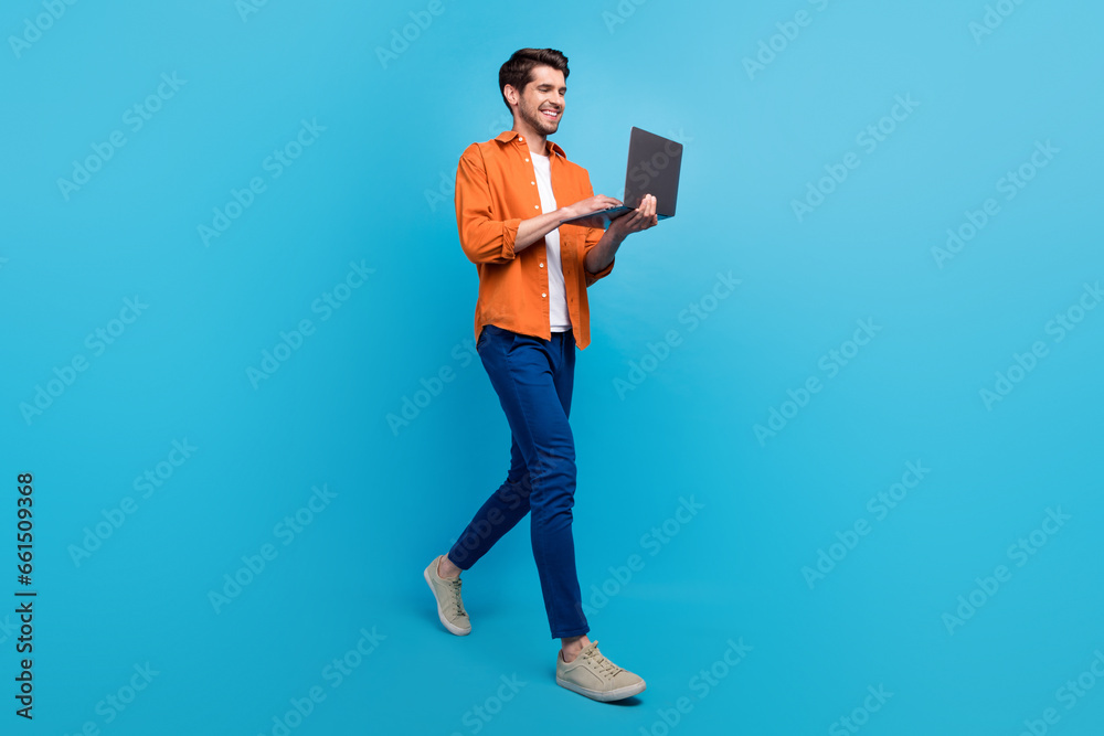 Poster full body profile photo of attractive cheerful young person hold use netbook walking isolated on blu