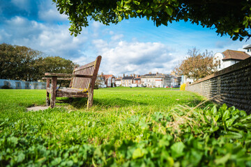 Shallow focus of a wooden park bench seen on lush grass. Located at the popular Suffolk, UK coastal town of Southwold during late summer.