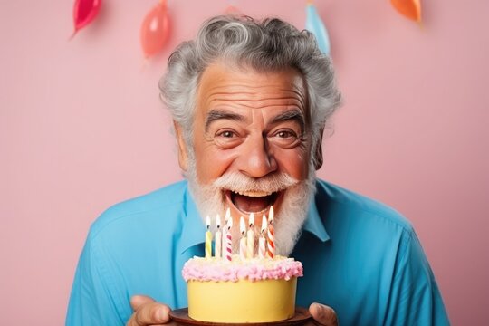 an mature man blowing out the candles on his birthday cake with a pink background