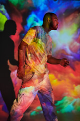 trendy bearded man moving on camera with closed eyes in digital projector lights, fashion concept