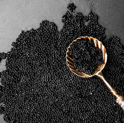 Black Caviar in golden spoon on caviar backdrop. High quality natural sturgeon black caviar...