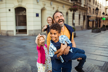Young mixed family having fun and walking downtown in the city - obrazy, fototapety, plakaty