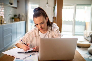Young woman going over her bills and payments on the laptop at home
