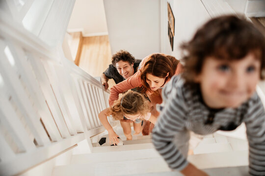 Young Family Climbing The Stairs Together At Home