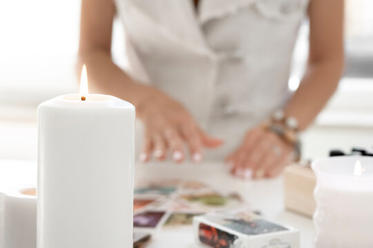 Tarot reader picking tarot cards.Tarot cards face down on table near burning candles . Tarot reader or Fortune teller reading and forecasting concept. 