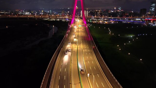 Aerial 4k video of Xinbei bridge at night. Cars passing through the bridge with colorful lights. New Taipei City, Xindian Sunshine Sports Park Sunshine Bridge.