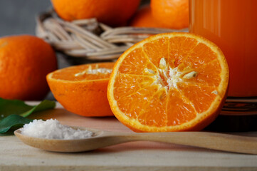 Close up photo of an orange cut in half. for making fruit juice with ingredients and equipment placed on a wooden chopping board