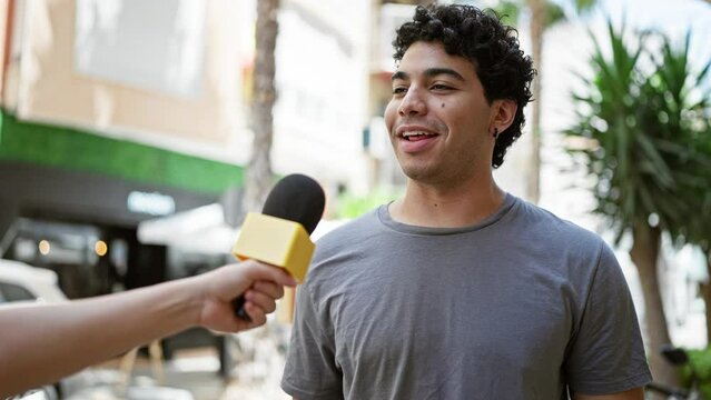 Young latin man having interview smiling at street