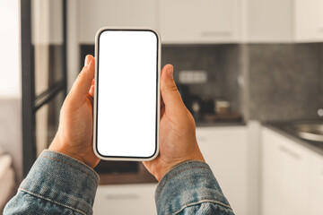 Kitchen background with hand with phone. Blurred home kitchen with blank smartphone screen