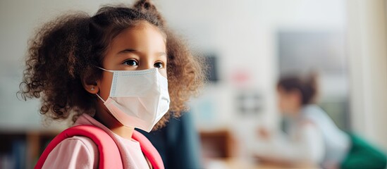 COVID 19 prevention measures in school include temperature checks medical screenings and social distancing with face masked students and a teacher using a thermometer at the preschool entra