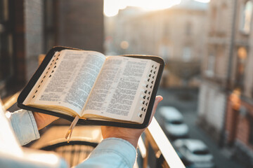 Bible in hands at dawn on the street, morning reading