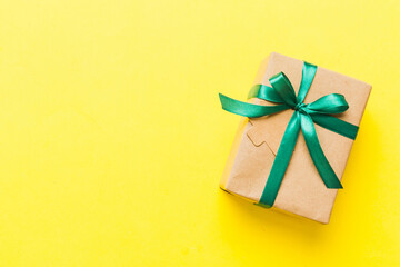 wrapped christmas or other holiday handmade present in paper with colored ribbon. Present box, decoration of gift on colourfull table, top view with copy space