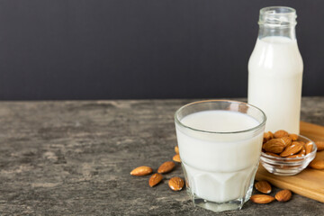 Top view of the almond milk in the glass bottle with almond nuts on the colored table. top view vith copy space
