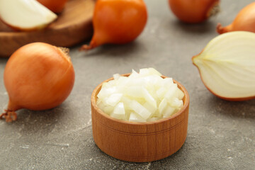 Fresh chopped onions on wooden bowl on grey concrete background
