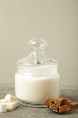Jar with white sugar on grey background. Space for text. Vertical photo