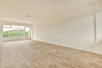 an empty living room with wood flooring and large windows looking out onto the trees that line the...