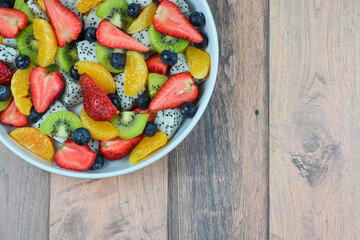 Fresh fruit salad bowl on wood grain table concept healthy food, to control weight, to lose weight