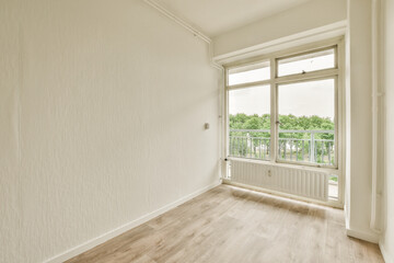 an empty room with wood flooring and white walls, looking out onto the balcony from the living room door
