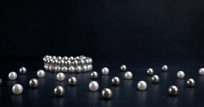 White and gray pearls and bracelets on black background. Fashion, accessories, jewelry, luxury, wealth concept. Dolly shot 4k