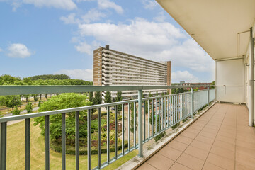 a balcony with some buildings in the background and green trees on the other side of the photo is clear blue sky