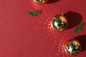 Golden shiny Christmas tree decoration baubles on the red background. Copy space