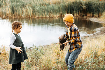 Little cute girl and boy catching a fish in the lake, river or pond. Funny kid wants to hold a fish...