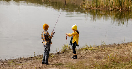 Little cute girl and boy catching a fish in the lake, river or pond.