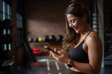 Happy Asian girl in sports clothes, reading the message on her phone with the good news, she smile